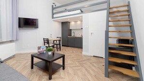 Un appartement moderne avec une chambre en mezzanine, un coin repas et une cuisine.