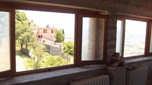 A room with large windows overlooking a building and greenery. - Farmhouse Il Palazzetto with a panoramic view (Campello sul Clitunno)