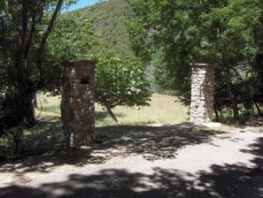 Un portón de piedra en un área boscosa con un sendero de tierra que lo atraviesa.