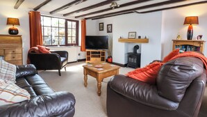 A cozy living room with a fireplace, leather sofas, a television, and a bookshelf.
