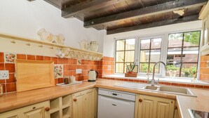 A kitchen with wooden cabinets, a dishwasher, a sink, and a window with a view of the outside.