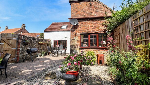A brick house with a patio, a stone wall, and a wooden fence.