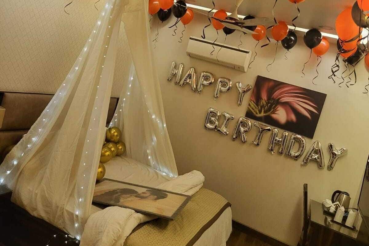 A bedroom with a bed, a canopy, balloons, and a 'HAPPY BIRTHDAY' sign.