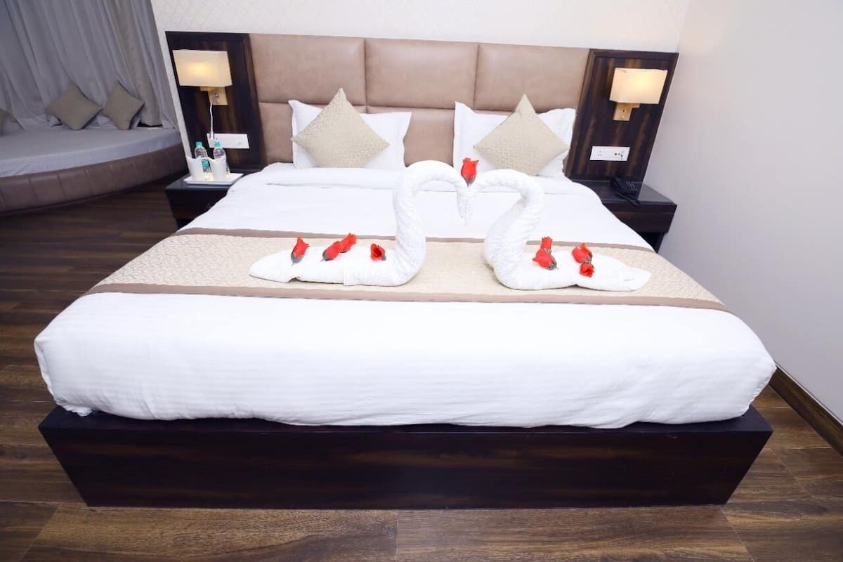 A hotel room with a large bed, two nightstands, a headboard, and decorative swan pillows.