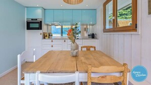 A dining area with a wooden table and chairs, a vase with flowers, and light blue cabinets.