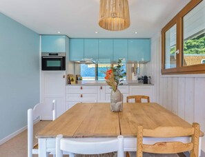 A dining area with a wooden table and chairs, a vase with flowers, and light blue cabinets.