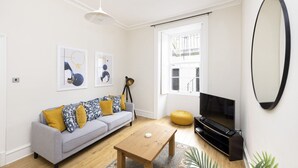 Uma sala de estar moderna com sofá cinza, mesa de centro de madeira e televisão.