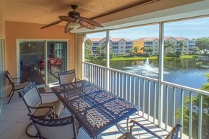 A balcony with a table and chairs, overlooking a body of water and buildings.