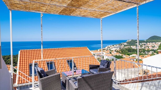 A terrace with wicker furniture and a view of the sea. - Andelic Sunset Apartments (Dubrovnik)