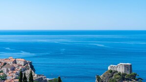 A coastal town with historic buildings and a prominent fort overlooking the sea. - Andelic Sunset Apartments (Dubrovnik)