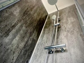 A shower with a handheld showerhead and a wall-mounted faucet.