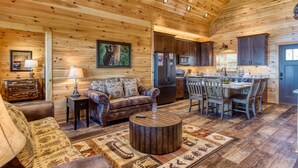 Un intérieur chaleureux de chalet en bois, comprenant un salon, un coin repas et une cuisine.