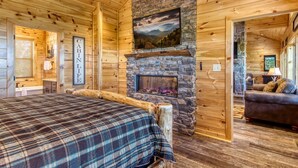 L’intérieur d’un chalet comprend un lit, une cheminée en pierre, des murs en bois et offre une vue sur les montagnes.