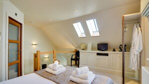 A bedroom with a bed, a desk, a TV, and a shower area. - Garden Stable: Cosy Stone Cottage with Parking (Alnmouth)