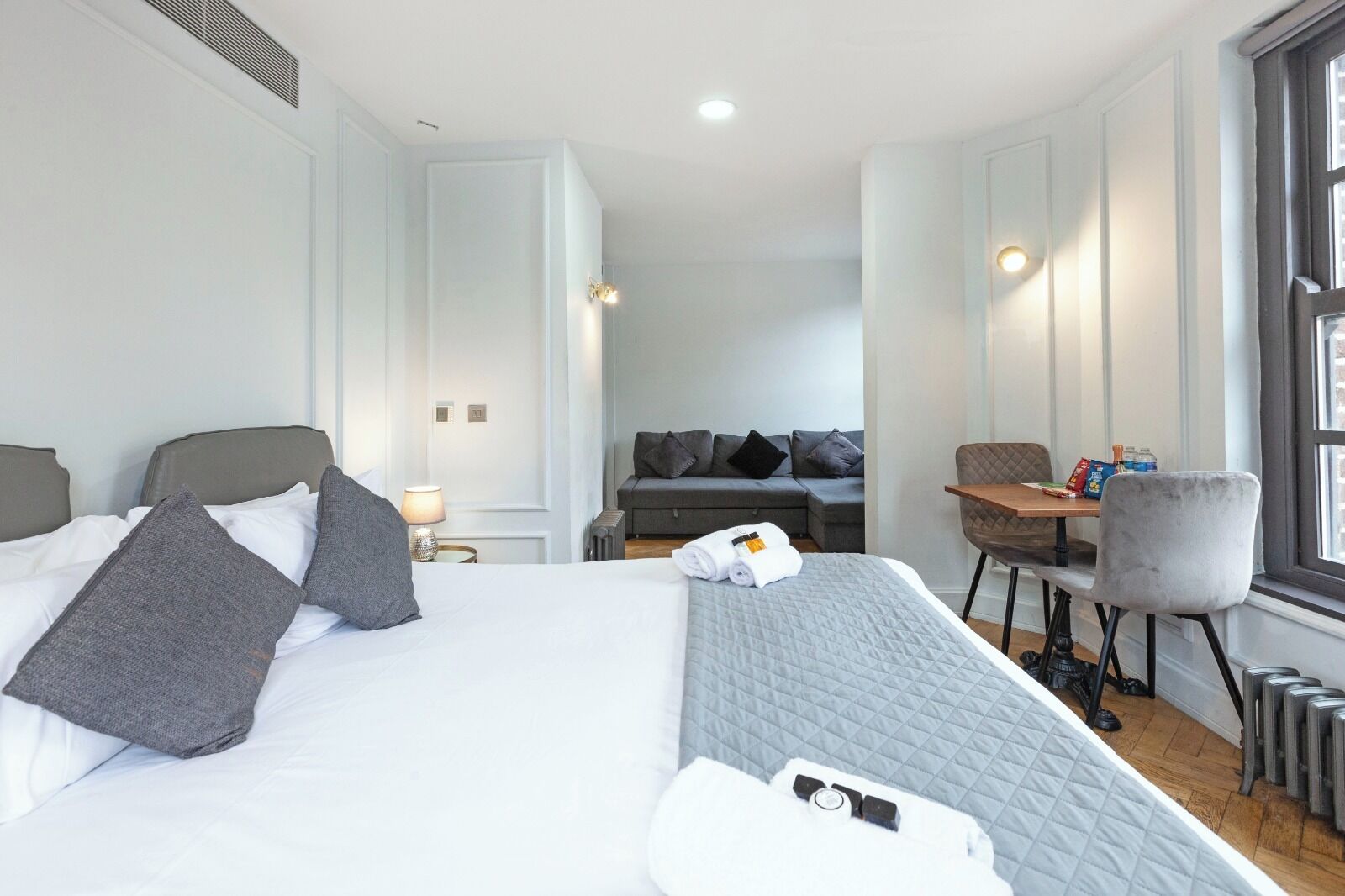 A hotel room with a large bed, a sofa, a table, and a chair.