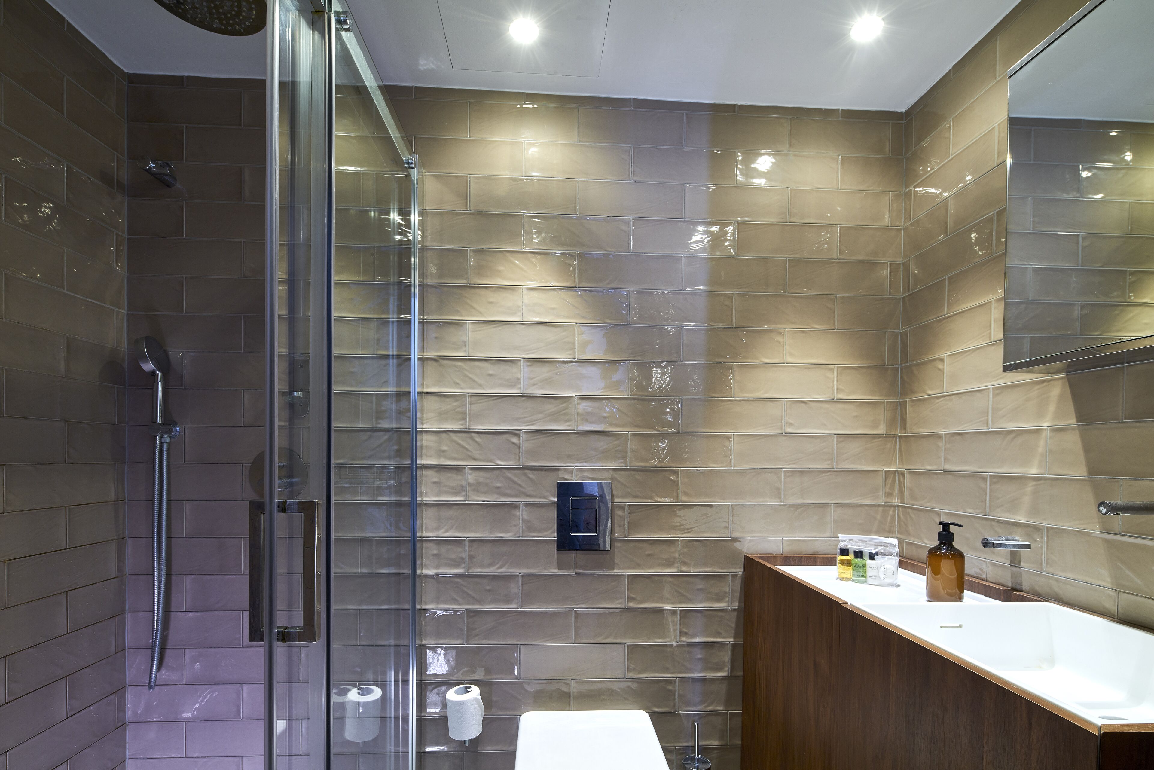A modern bathroom with a glass-enclosed shower, a wooden vanity, and a large mirror.
