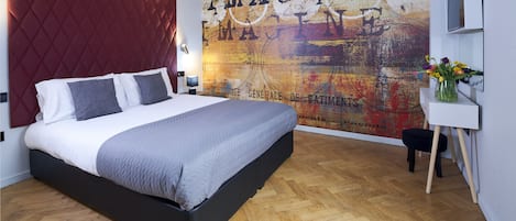 A modern bedroom with a large bed, a red headboard, a wall mural, and a small table with a vase of flowers.