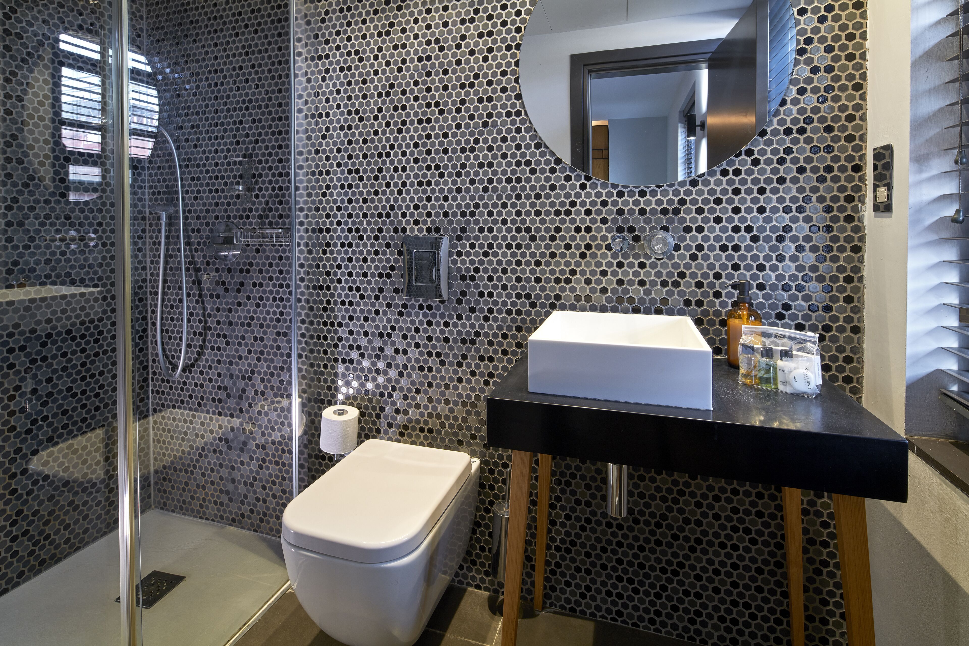 A modern bathroom with a glass-enclosed shower, a toilet, and a sink with a mirror above it.