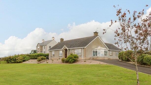 A two-story house with a well-maintained lawn and a driveway leading to the entrance. - Braeside Farm House (Ballymena)