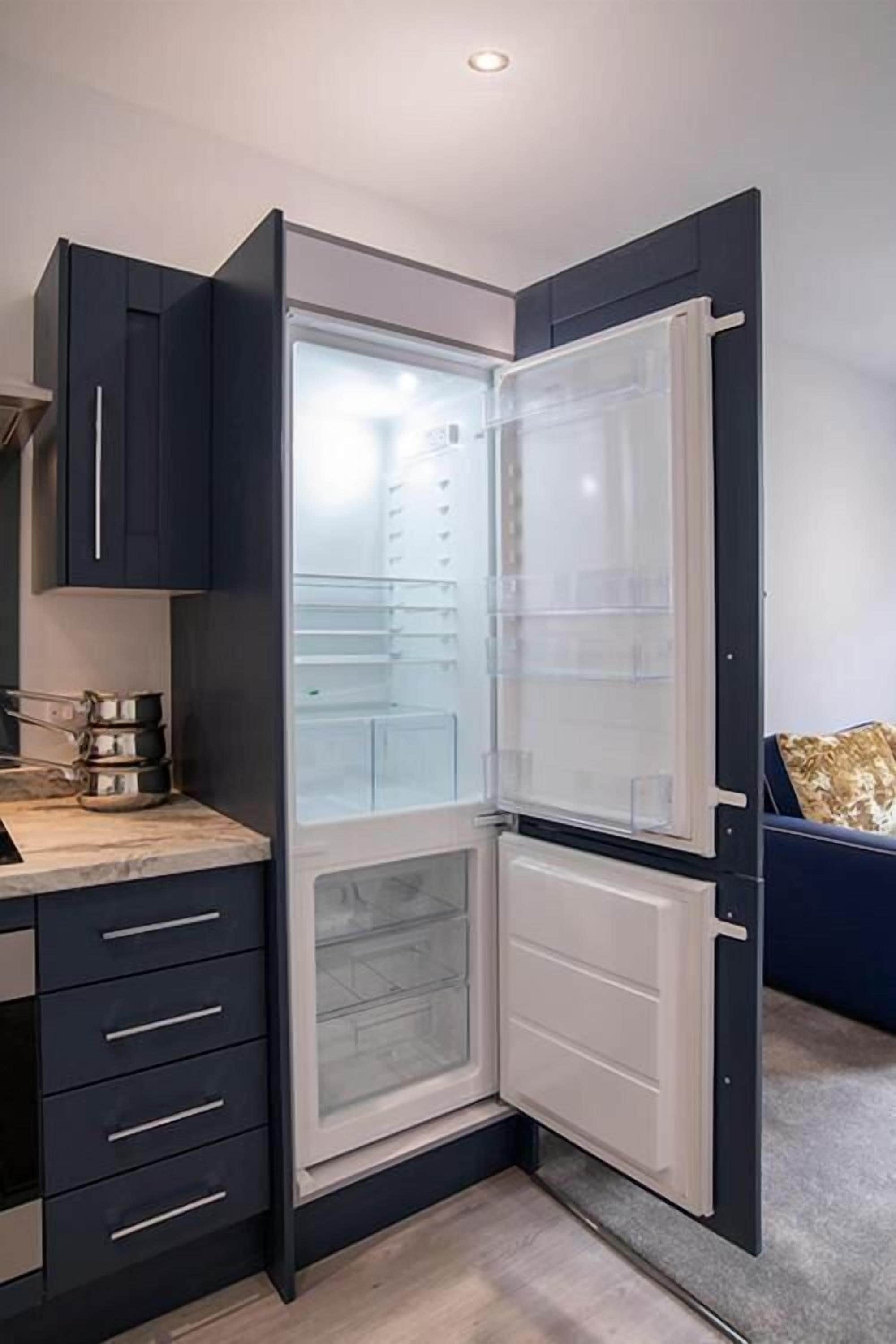 A modern kitchen with a built-in refrigerator, a countertop with kitchenware, and a dark-colored cabinet.