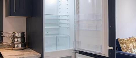 A modern kitchen with a built-in refrigerator, a countertop with kitchenware, and a dark-colored cabinet.