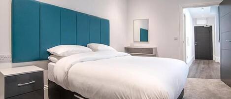 A modern bedroom with a large bed, a nightstand, and a dresser.