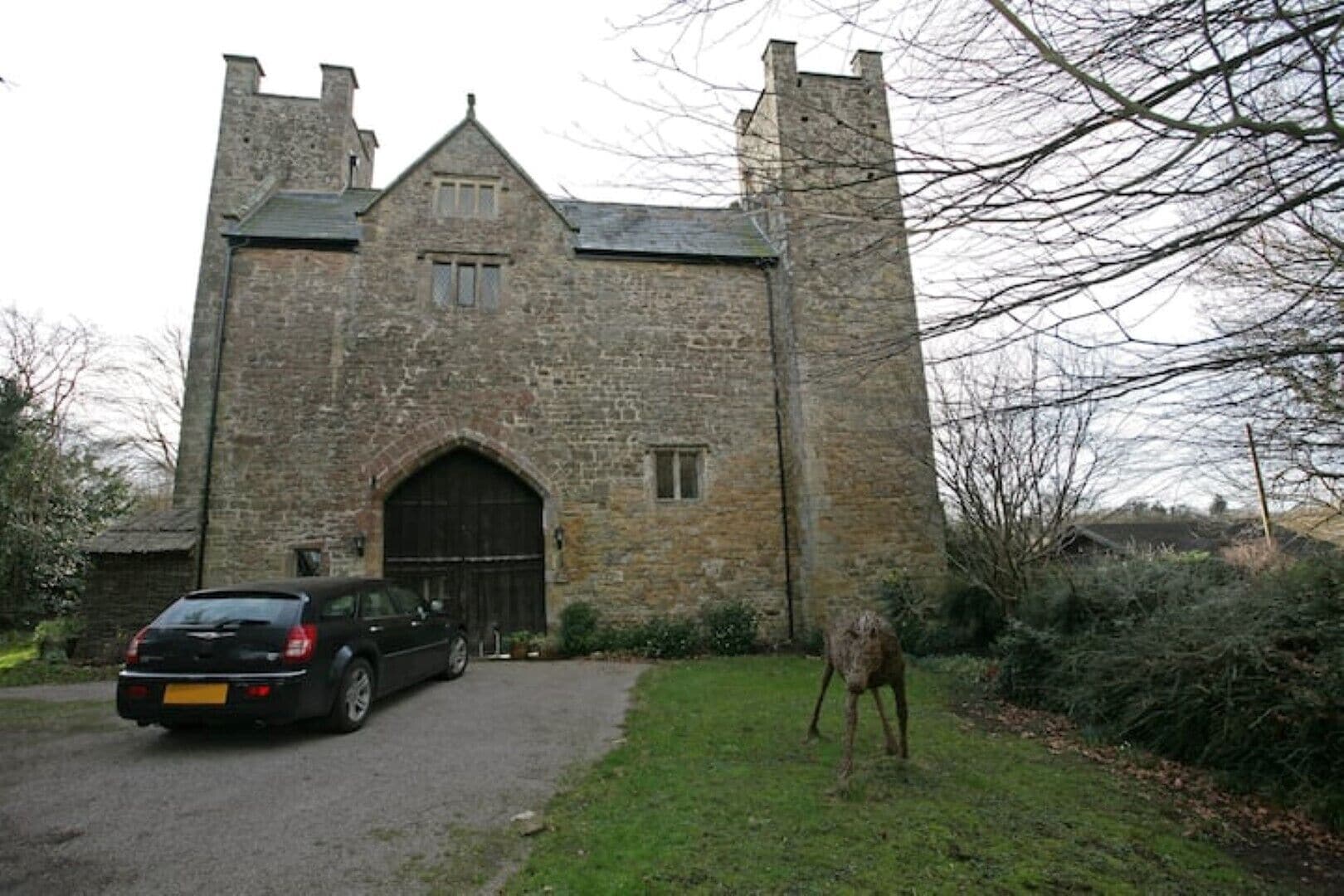 A stone building with a large arched entrance and a car parked in front.