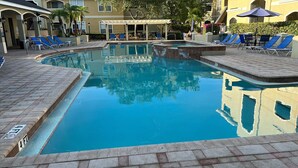 A swimming pool with blue water, surrounded by lounge chairs and a covered seating area.