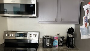 A kitchen with stainless steel appliances, including a microwave, oven, and toaster. There is a coffee maker and a sign indicating a smoking area.