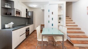 A modern kitchen with a dining area, featuring a glass table and white chairs, a microwave, and a coffee maker. - Aquamarine Terrace by Wonderful Italy (Siracusa)