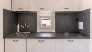 A modern kitchen with a built-in sink, a window, and a door leading to another room. - Aquamarine Terrace by Wonderful Italy (Siracusa)