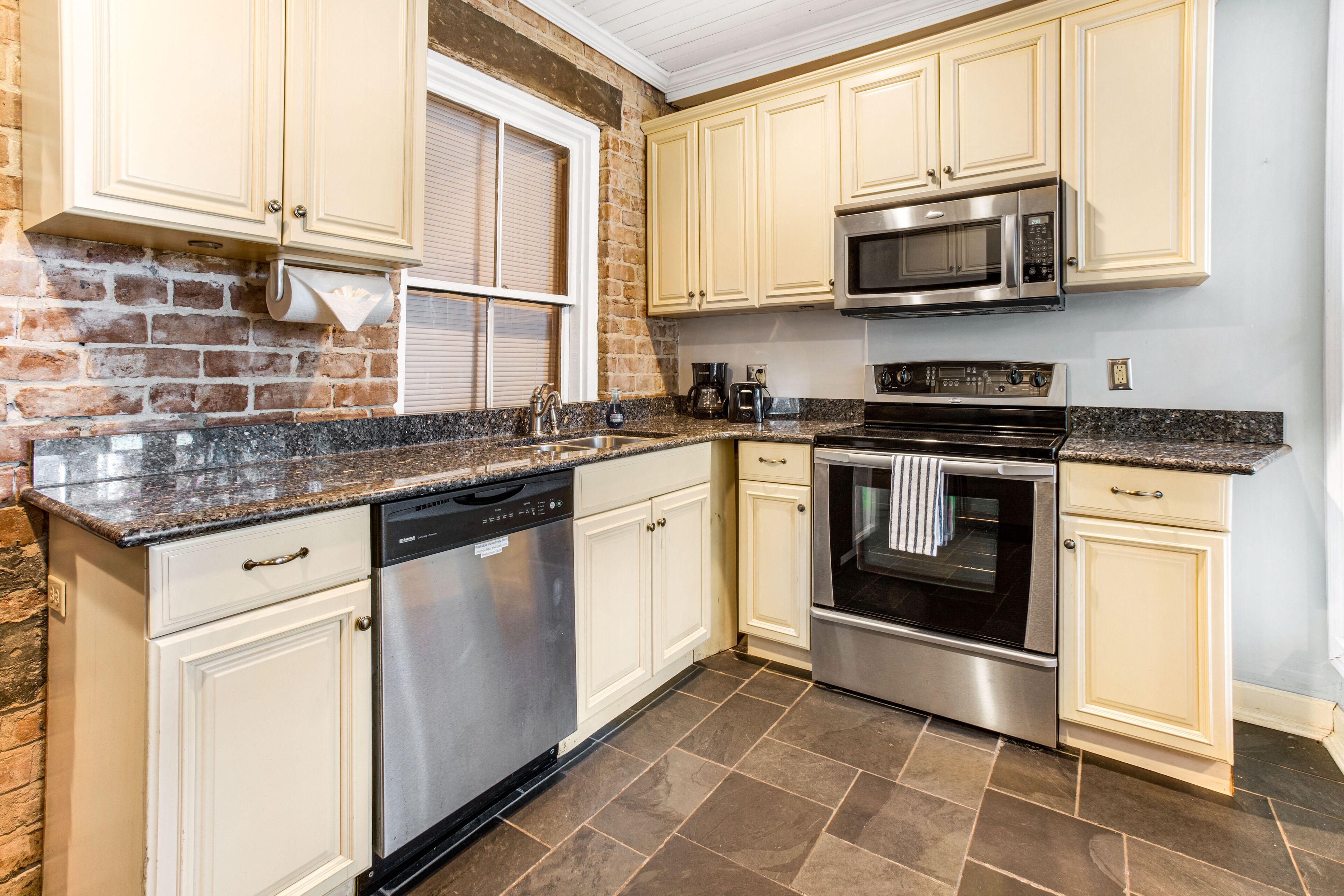 A kitchen with white cabinets, a stainless steel dishwasher, a microwave, and an oven.