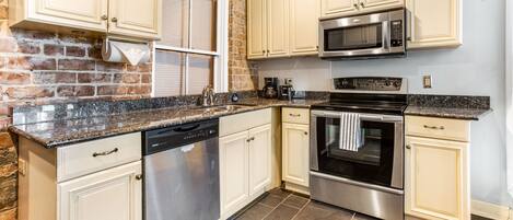A kitchen with white cabinets, a stainless steel dishwasher, a microwave, and an oven.