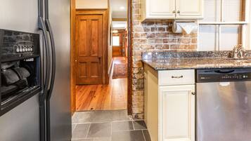 A kitchen with a stainless steel refrigerator, a dishwasher, and a granite countertop.