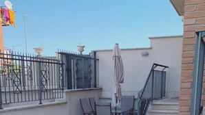 A rooftop patio with a table and chairs, a small umbrella, and a metal railing. - Extraordinary vacations (Villa Verde)