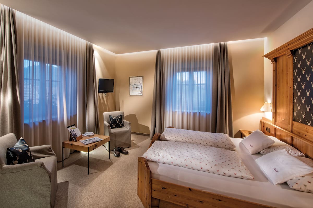 Een hotelkamer met een bed, twee stoelen, een tafeltje en een televisie.