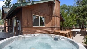 Eine Holzhütte mit Whirlpool, Sitzgelegenheiten im Freien und einer Terrasse.