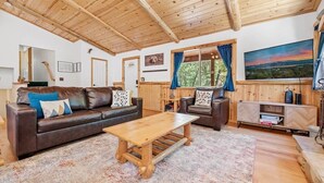 Ein gemütliches Wohnzimmer mit Holzbalkendecke, Ledersofas, einem Couchtisch aus Holz und einem Bild an der Wand.