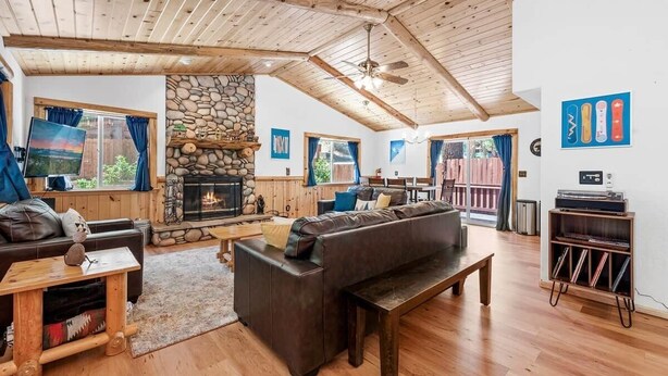 Ein gemütliches Wohnzimmer mit Kamin aus Stein, Holzboden und einer großen Couch.