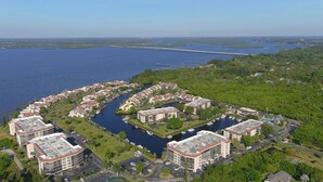 Vue aérienne d’une station balnéaire comprenant plusieurs bâtiments, un port de plaisance et une végétation luxuriante.