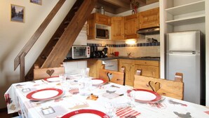 A kitchen with wooden cabinets, a microwave, a stove, and a refrigerator. - 10m from resort center, 2nd floor, balcony, tv, ski locker, 42m², Aussois (Aussois)