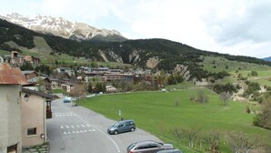A mountain town with buildings, a road, and a green field. - 10m from resort center, 2nd floor, balcony, tv, ski locker, 42m², Aussois (Aussois)