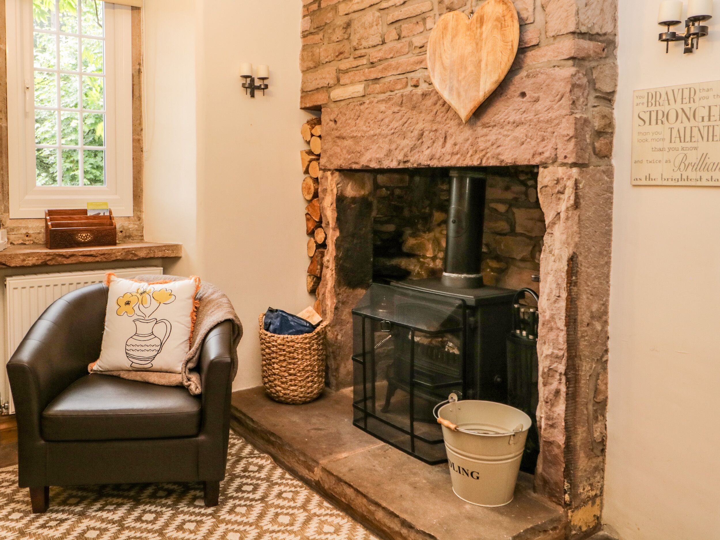 A cozy room with a stone fireplace, a leather chair with a cushion, a woven basket, and a bucket.
