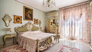 A classic bedroom with a large bed, ornate furniture, and decorative elements like curtains and wall art.