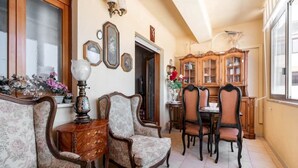 A dining area with a wooden table and chairs, a patterned sofa, and a cabinet with glass doors.
