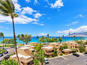 A resort with multiple bungalow-style buildings, a parking lot, and a view of the ocean. - Prime Kihei 2BR Condo Breathtaking Panoramic Ocean Views Kamaole I Beach (Kihei)