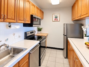A kitchen with wooden cabinets, stainless steel appliances, a microwave, oven, and refrigerator.