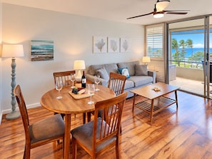 A dining area with a wooden table, chairs, and a view of the ocean through large windows.