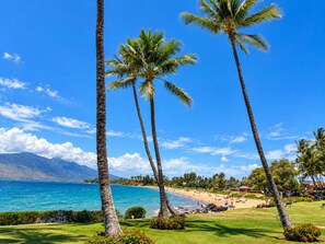 A beach with palm trees, a clear sky, and a view of the ocean. - Prime Kihei 2BR Condo Breathtaking Panoramic Ocean Views Kamaole I Beach (Kihei)