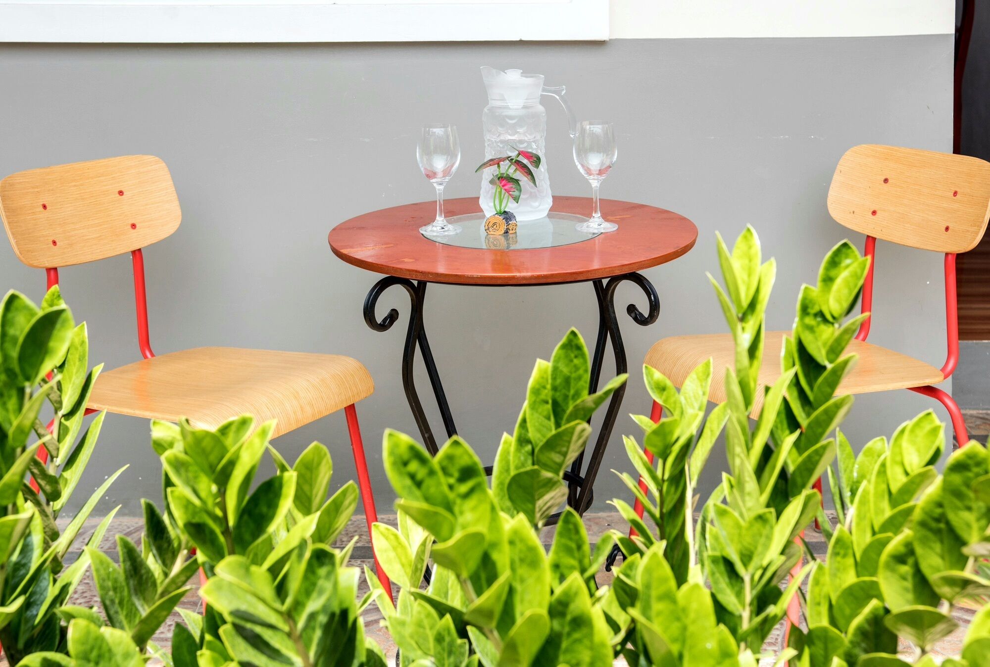A small round table with two chairs, a pitcher, and two glasses.